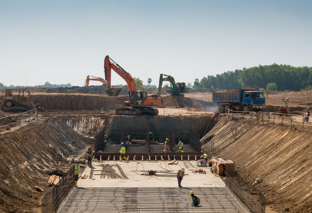 A close shot of heavy machines and construction workers working on a building